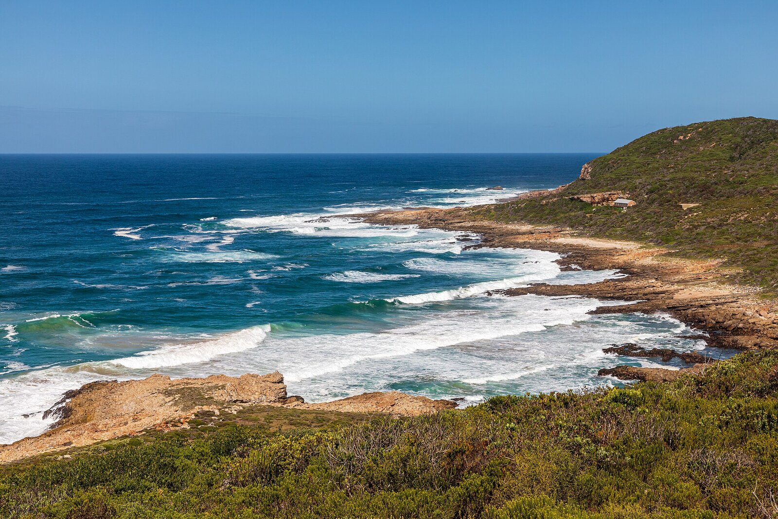 A traveller at a scenic viewpoint over the coast at golden hour on the Garden Route