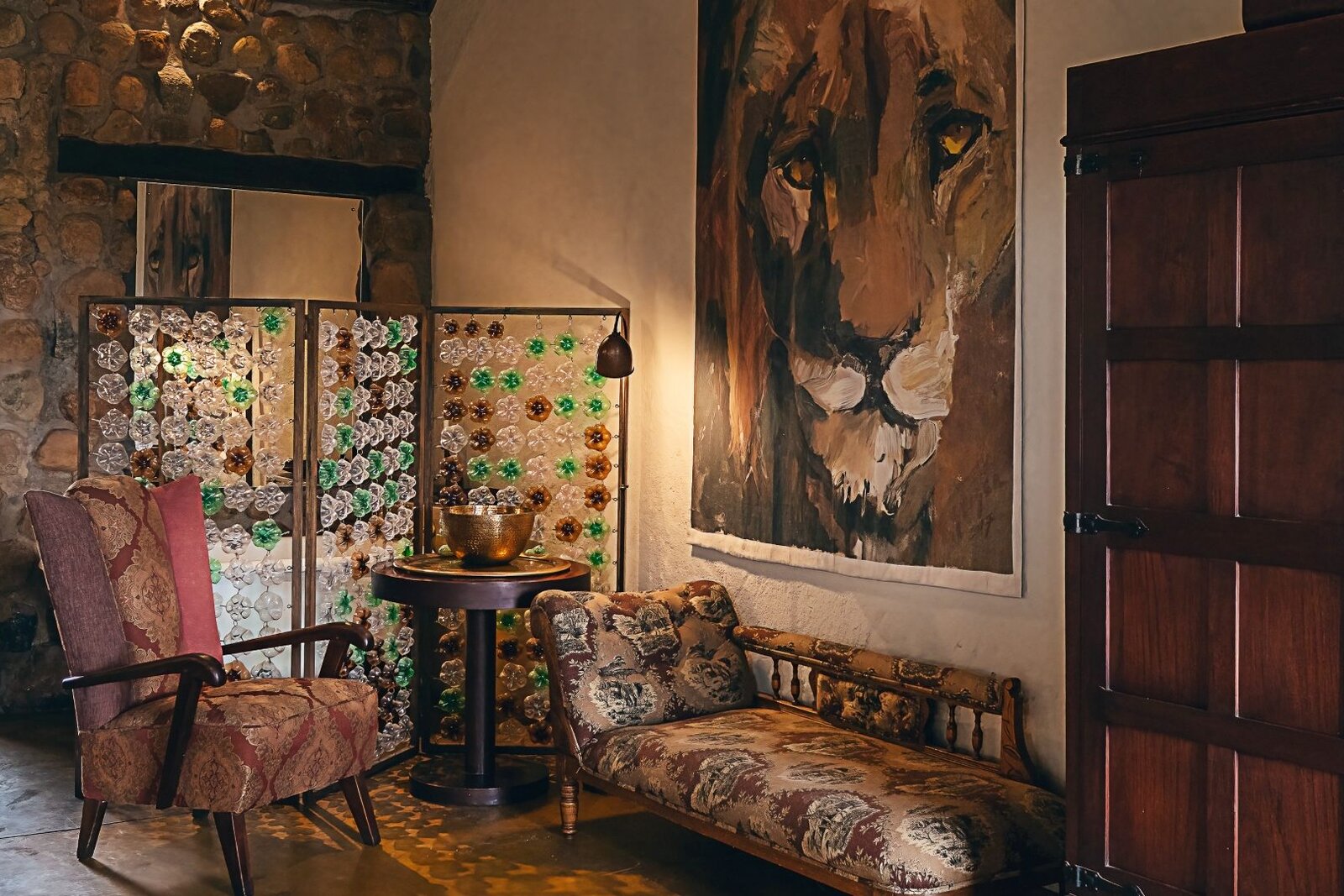 Sitting area at Geiger's Camp with a large lion painting over a vintage chaise, Timbavati