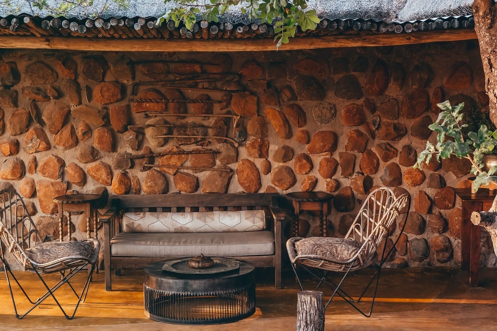 Lounge at Geiger's Camp with a lit fireplace and pink velvet wingback chairs, Timbavati