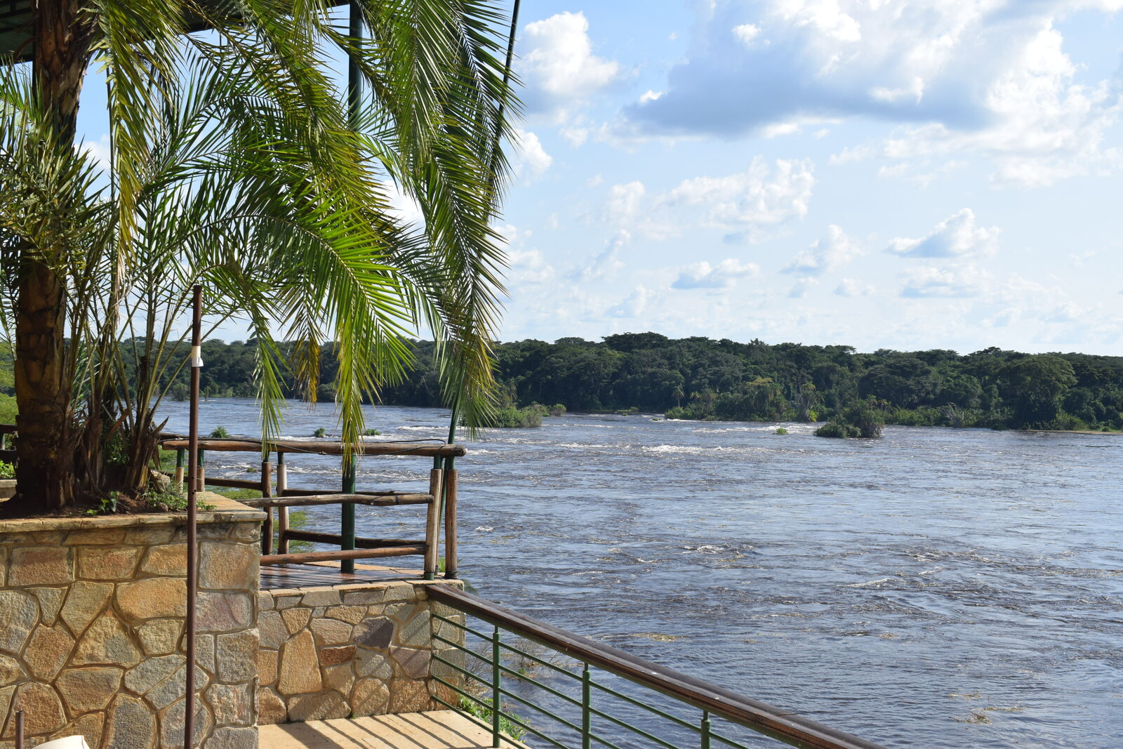 A safari lodge deck extending over a river at golden hour, set for a wedding celebration