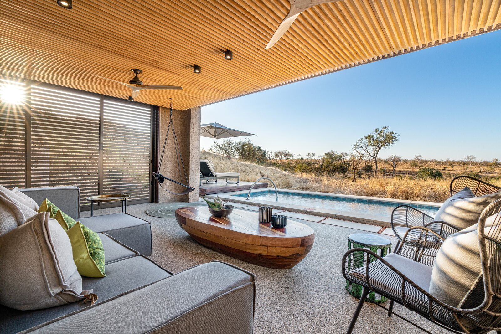 A luxury safari lodge deck with a plunge pool overlooking the African bush at sunset