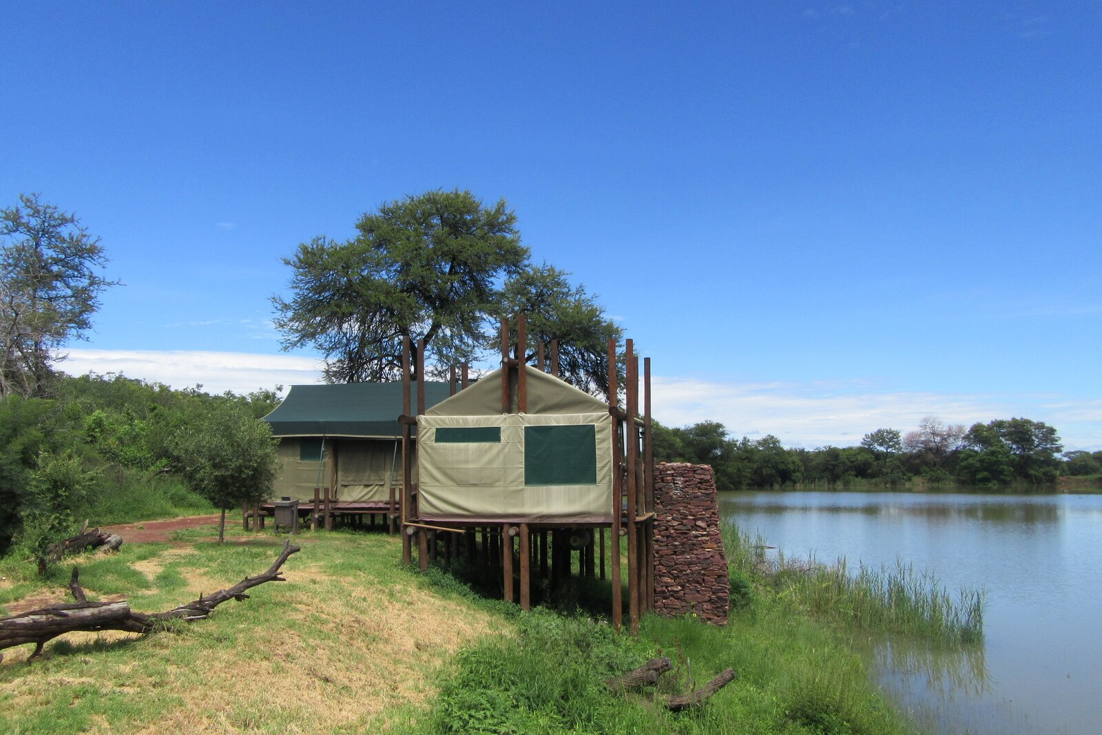 A tented camp raised beside a stretch of water