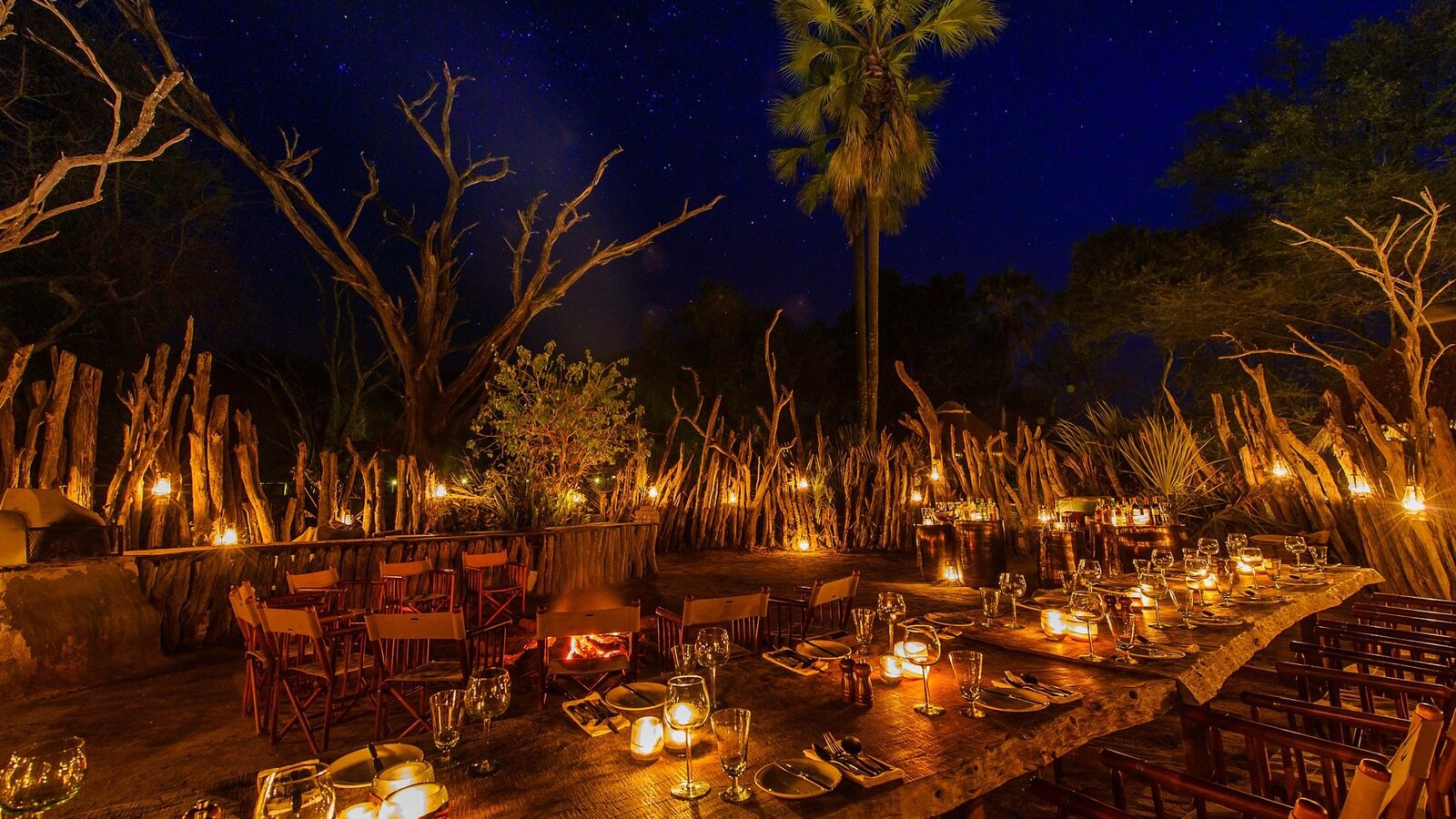 A luxury tented camp set for candlelit dining beneath the palms in Botswana