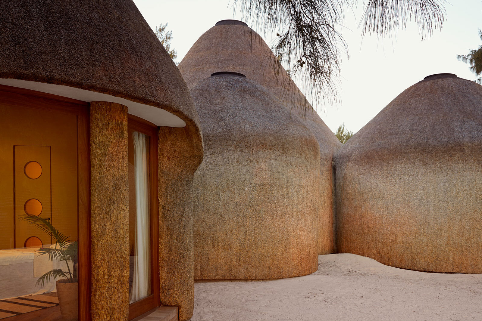 A Kisawa Sanctuary residence with thatched roofs rising from the forest and dune on Benguerra Island, Mozambique