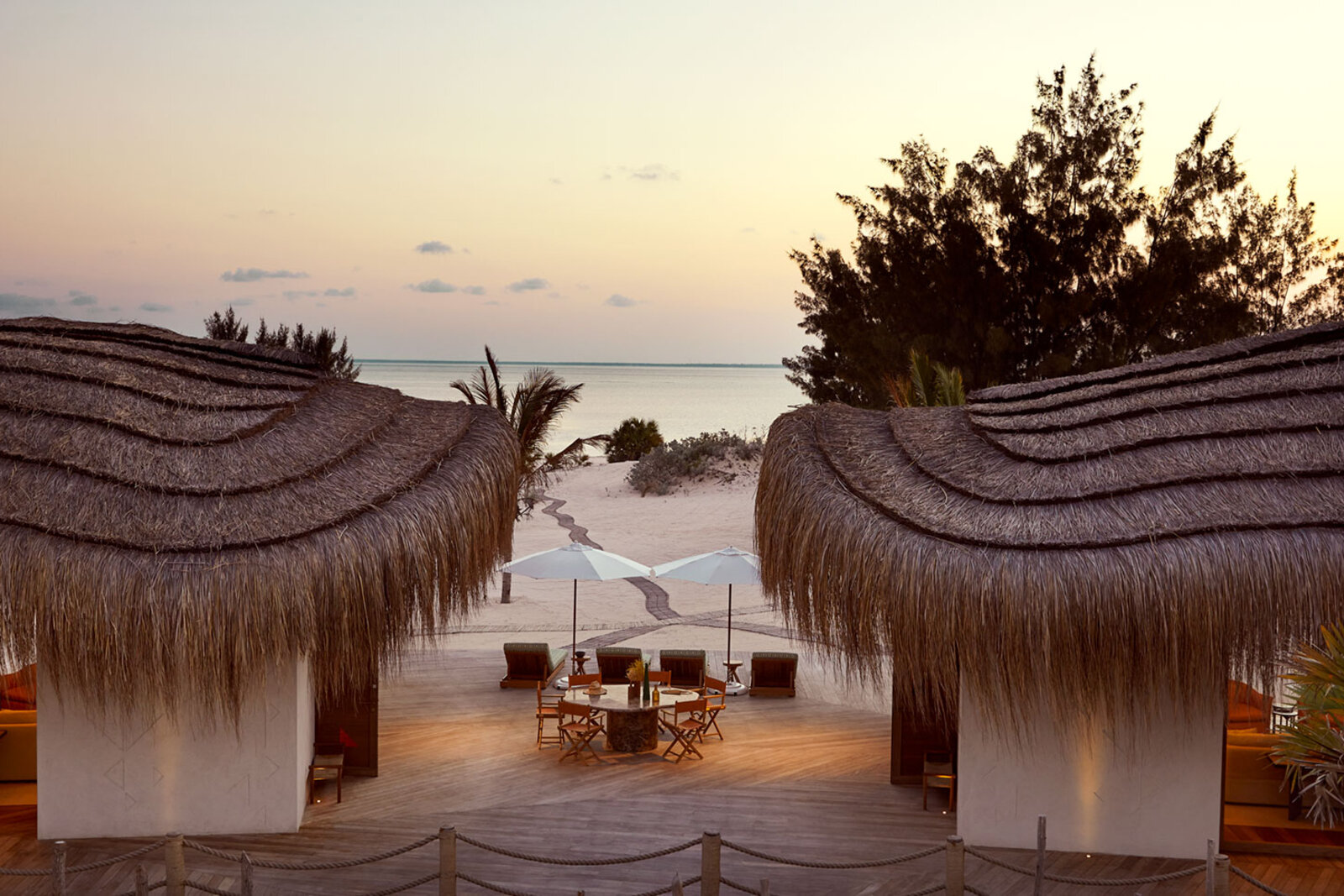 Kisawa Sanctuary pavilions and terrace glowing at sunset over the Indian Ocean, Benguerra Island, Mozambique