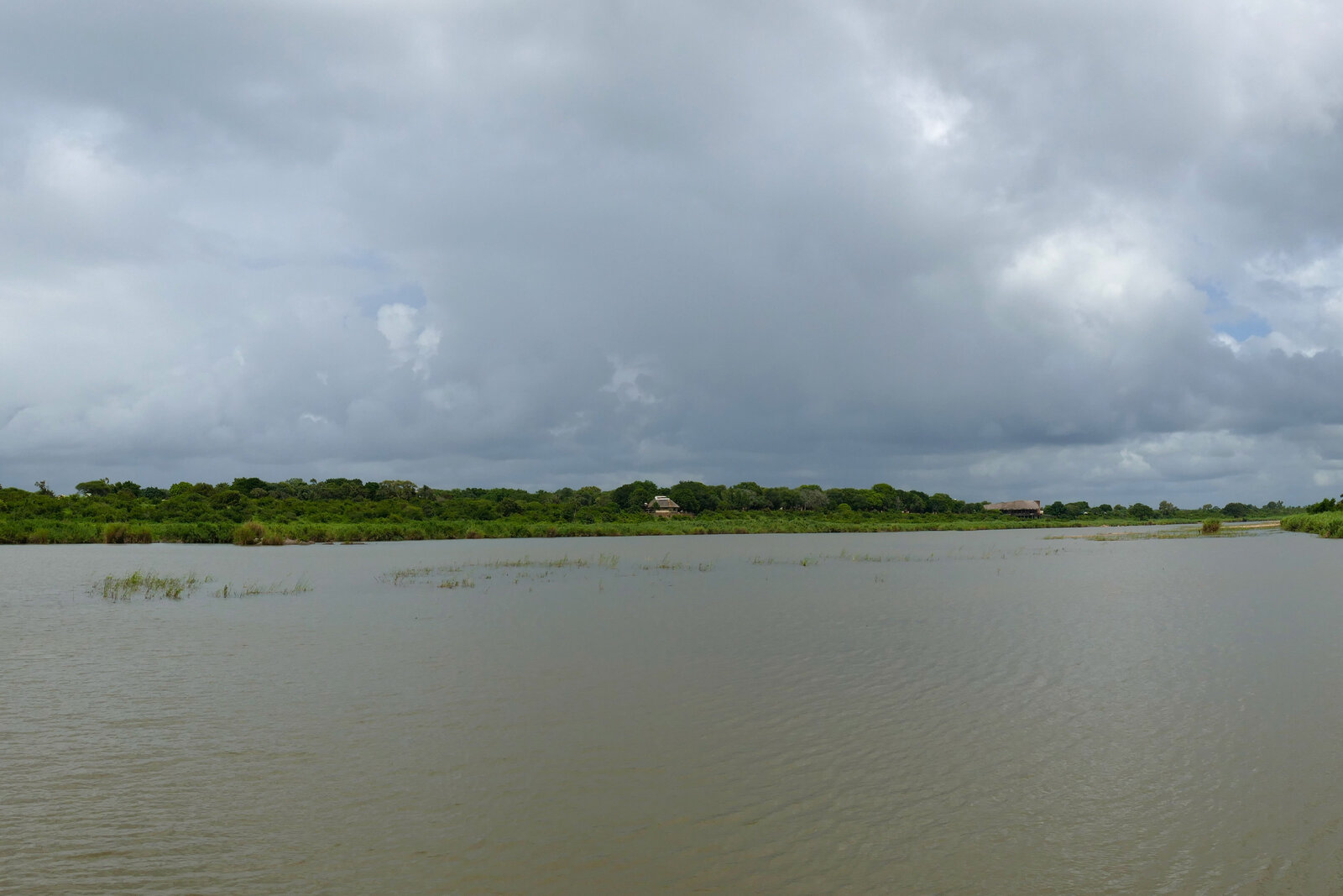 A river and floodplain under heavy grey storm clouds