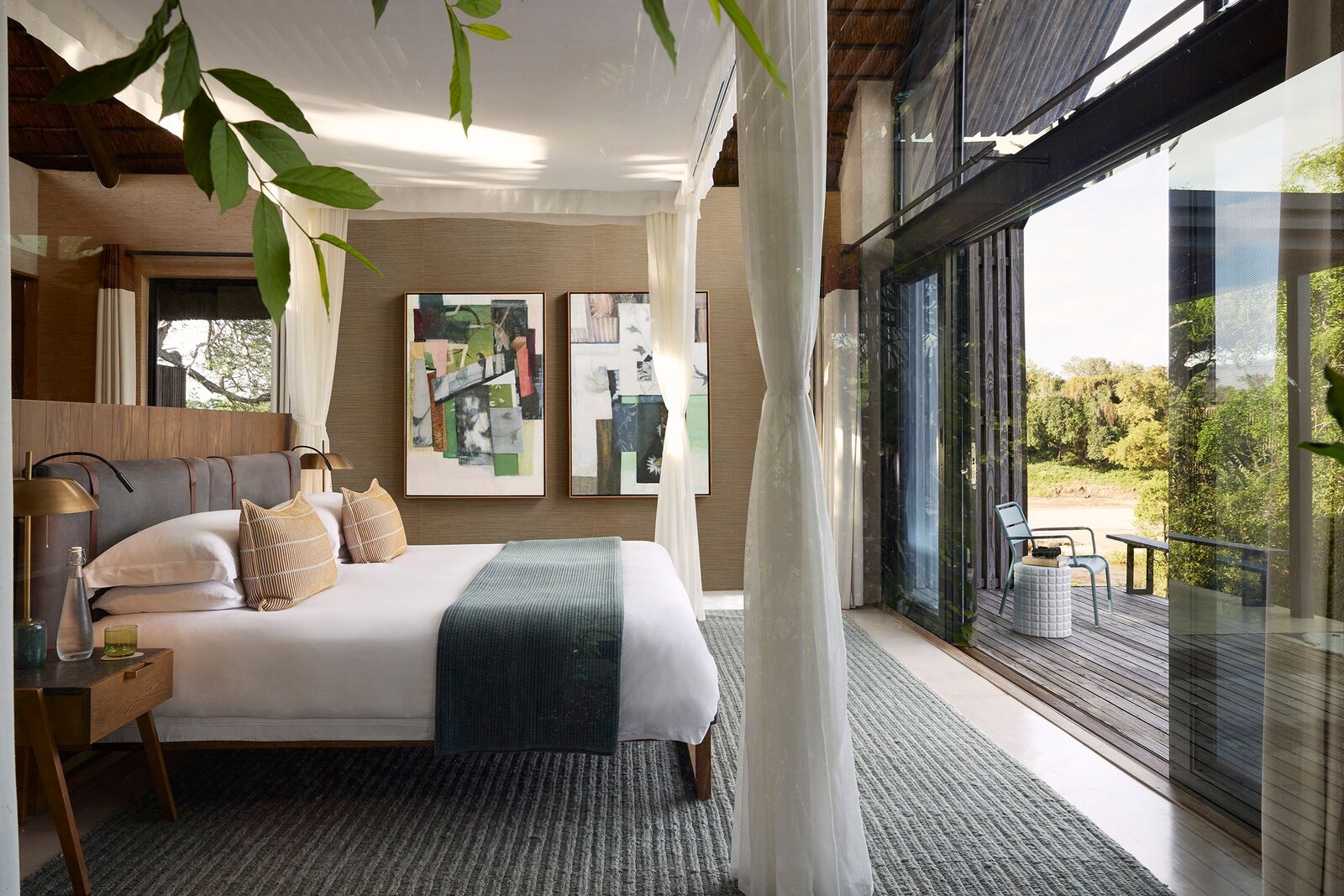 Lion Sands Ivory Lodge suite bedroom with floor-to-ceiling glass and draped bed