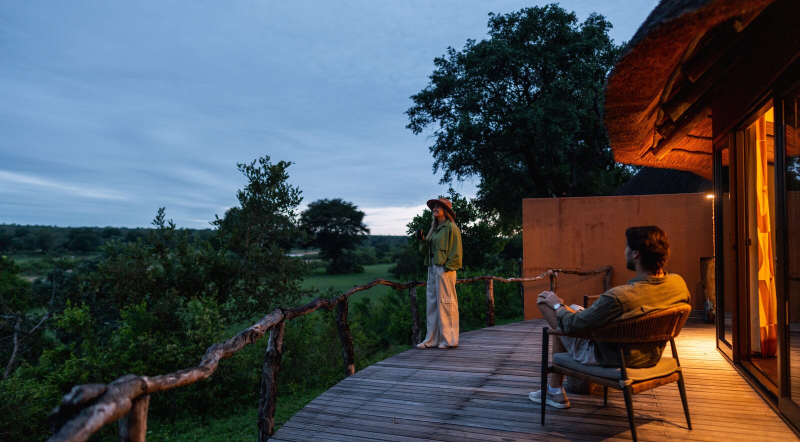 Guests relaxing on a private deck at MalaMala at golden hour overlooking the riverine bush