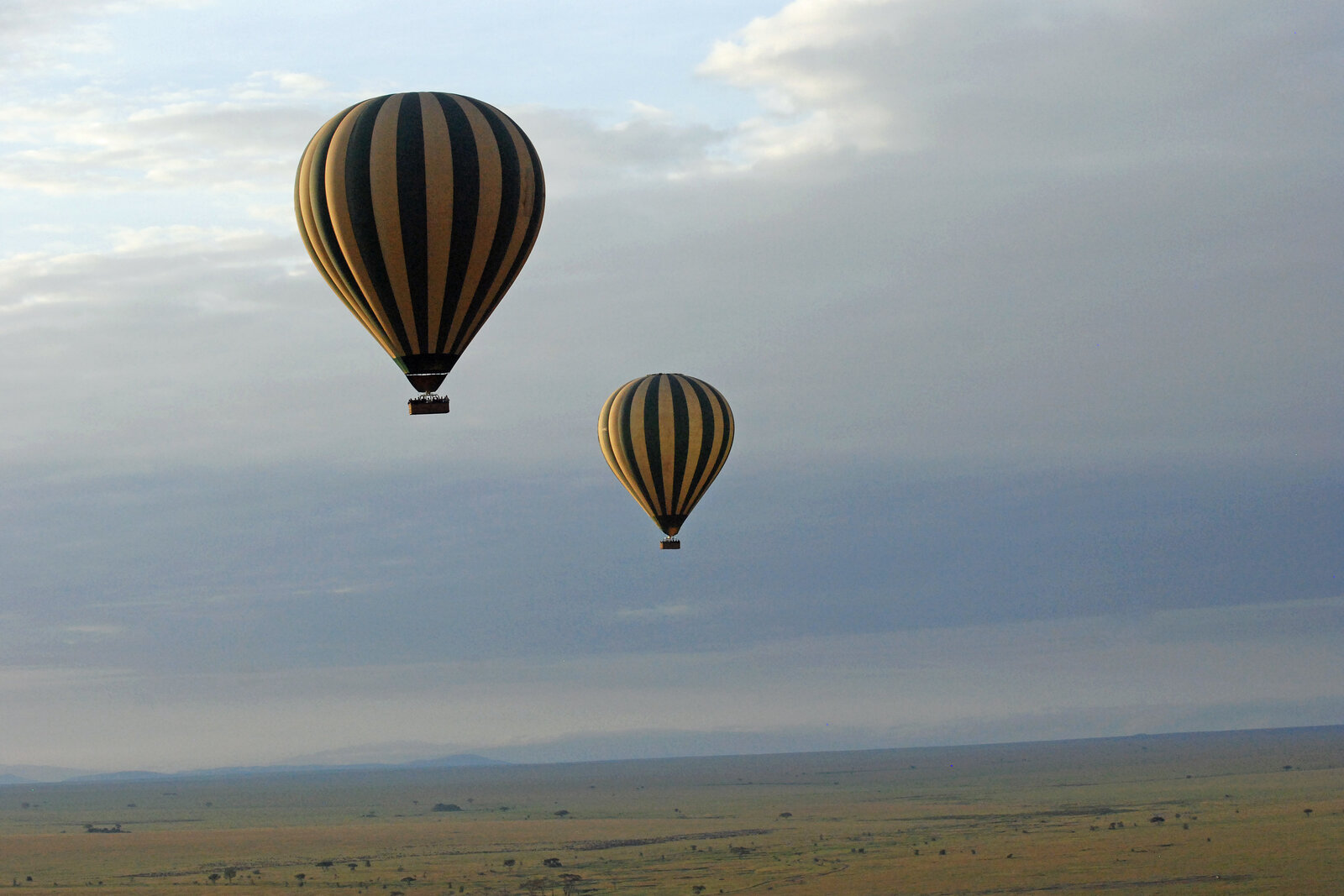 A hot air balloon drifting over the Mara plains at sunrise