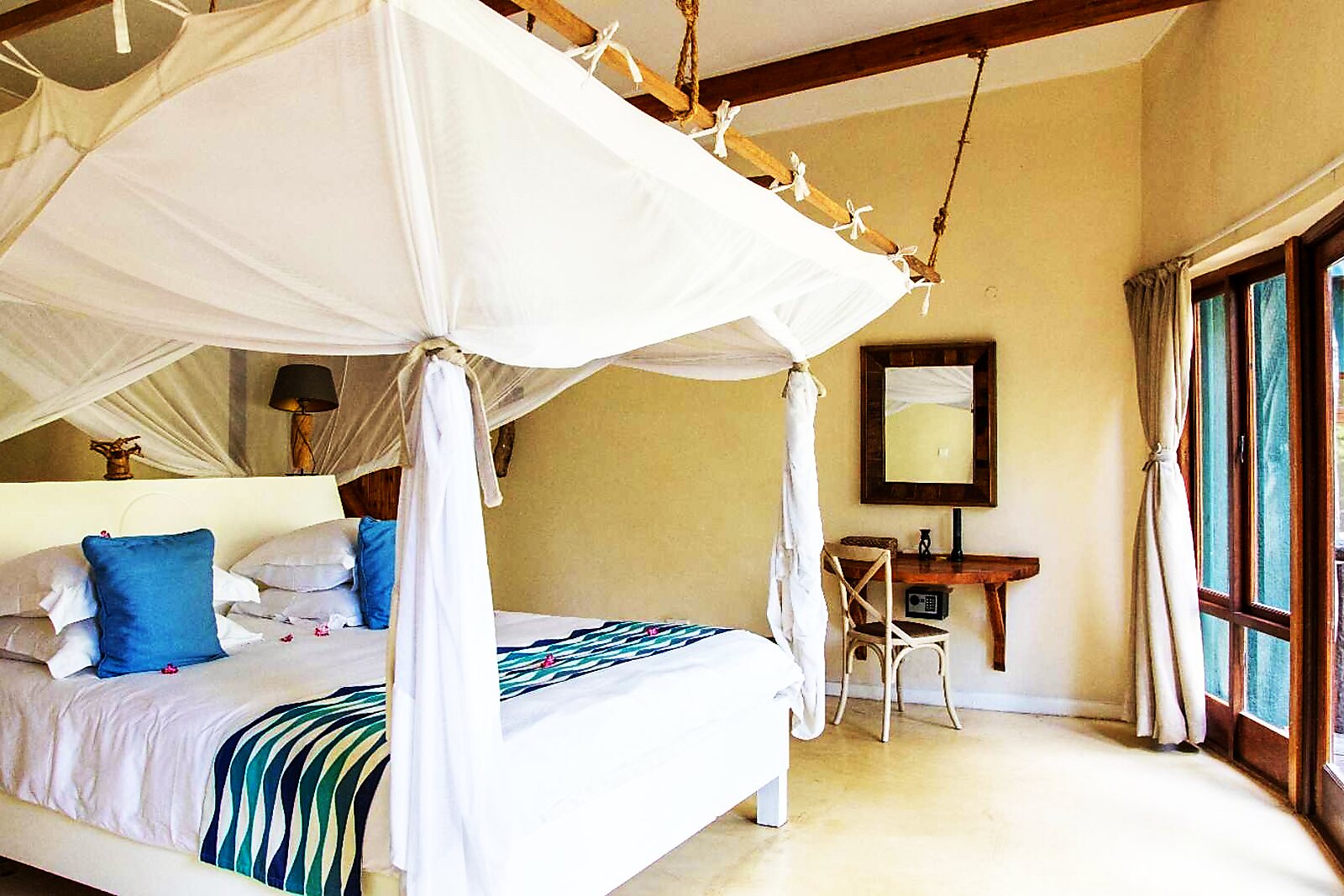 A netted four-poster bed in a villa with lake views at Pumulani