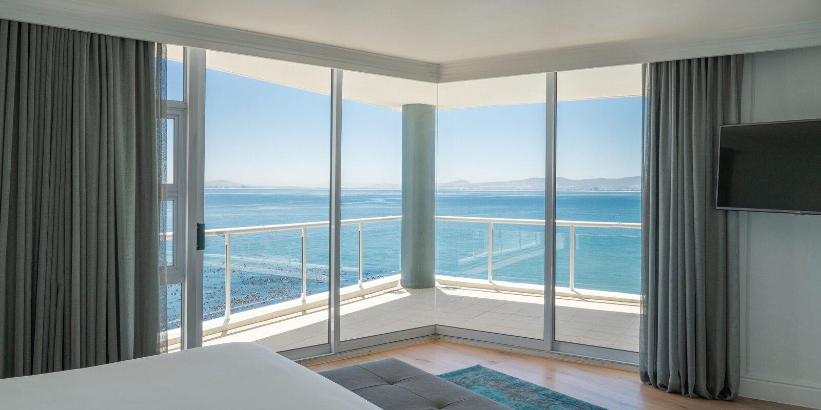 A corner room at the Radisson Collection Waterfront with floor-to-ceiling glass and a balcony over the Atlantic