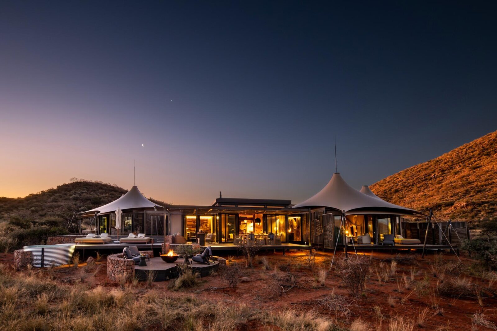 Luxury tented camp glowing at dusk in the red Kalahari dunes