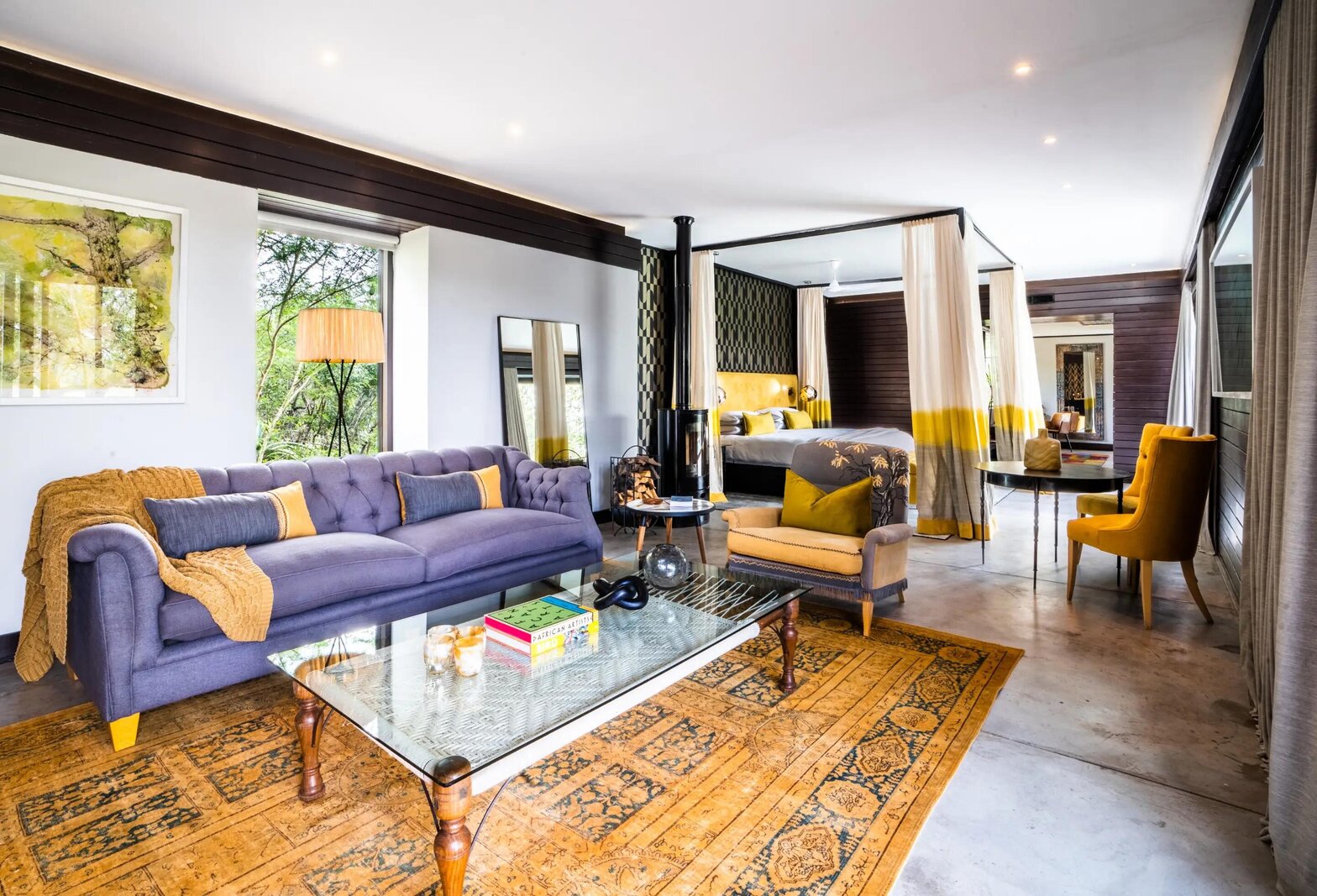 A Silvan Safari lounge with a purple velvet sofa, mustard armchairs, a patterned rug and contemporary art