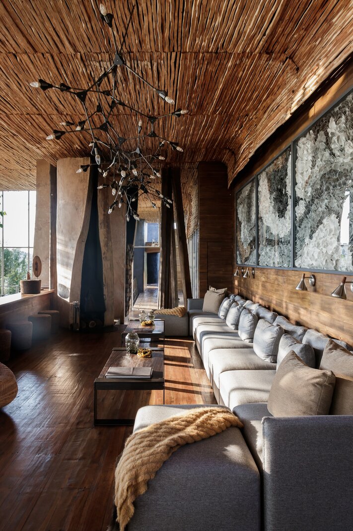 Singita Lebombo main lodge lounge with timber ceiling, sculptural chandelier and river views