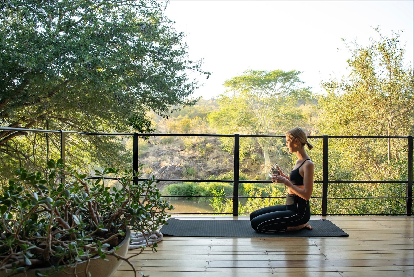 Guest practising yoga on a Singita deck overlooking the eastern Kruger bush