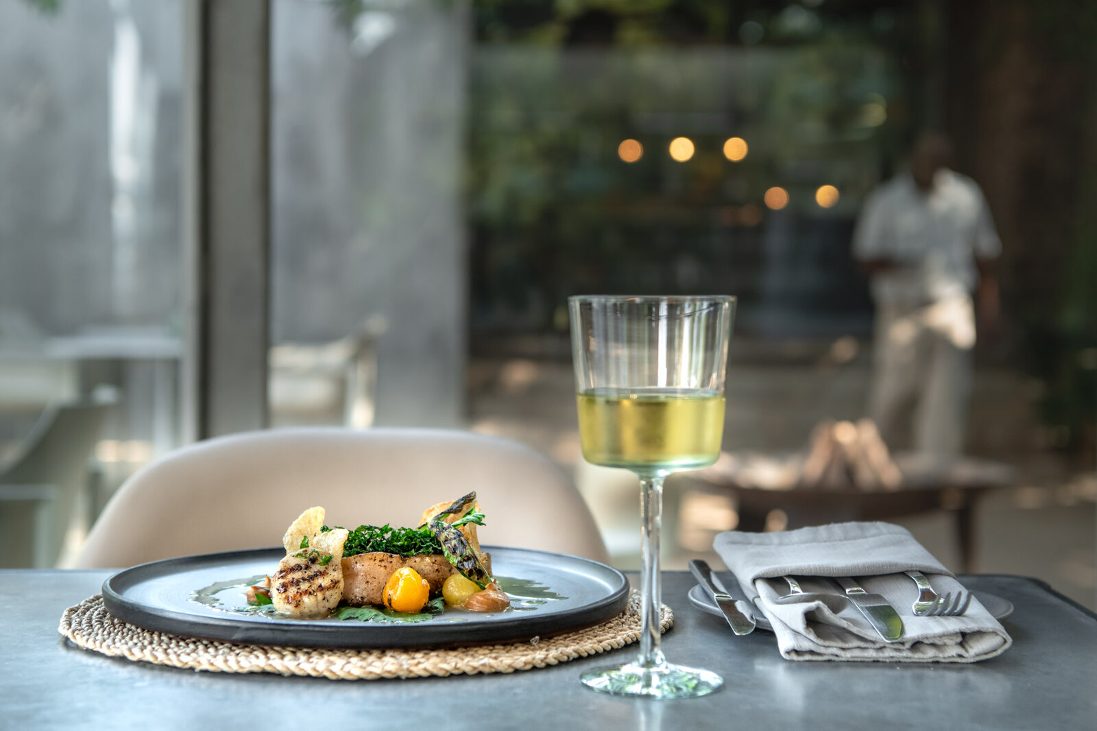 Beautifully plated Singita dish with a glass of white wine on a bush deck