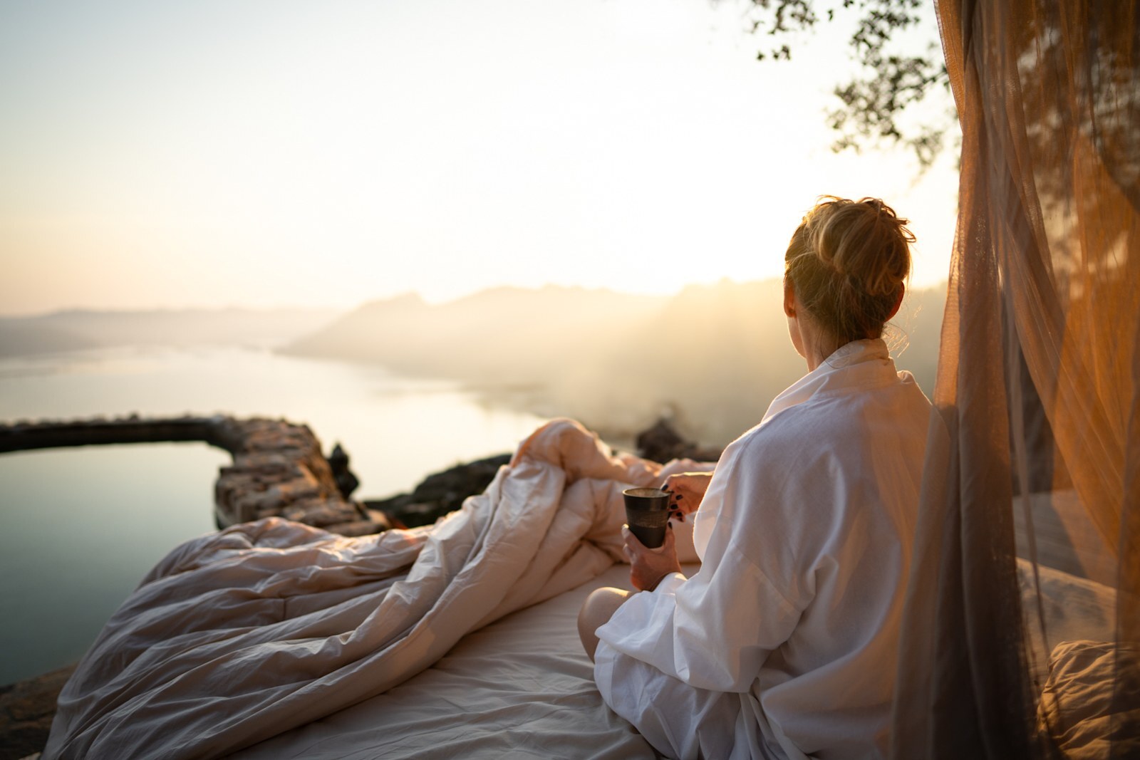 A guest on a star-bed sleep-out overlooking the Malilangwe Dam at dawn