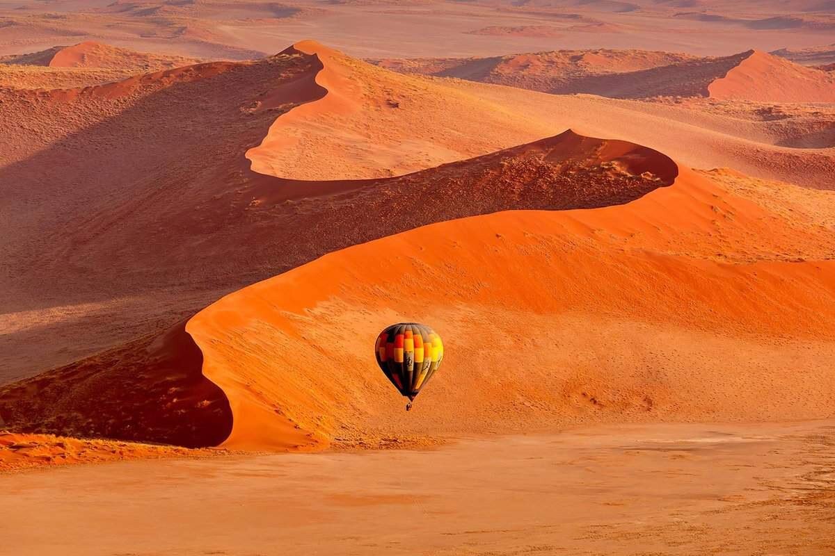 A hot-air balloon drifting over the Namib desert at dawn