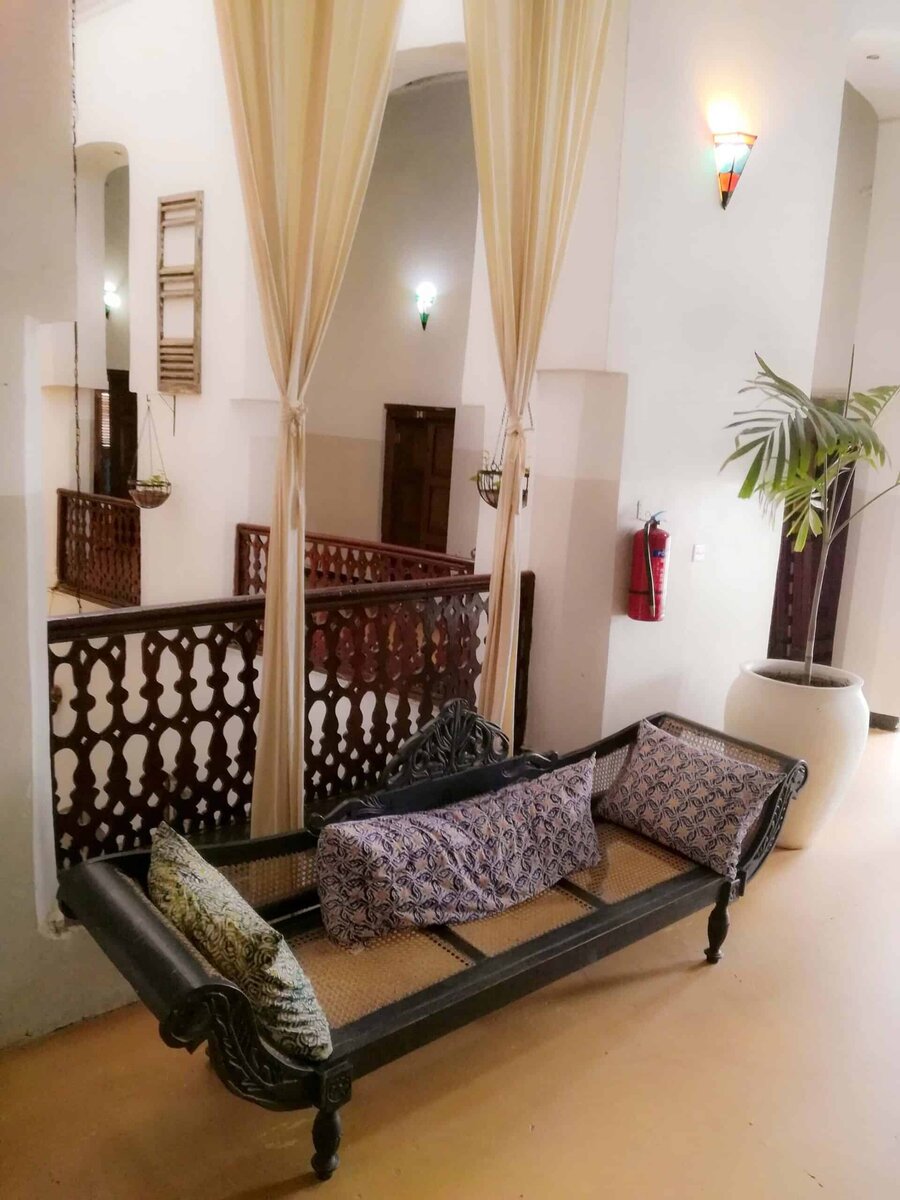 Carved Zanzibari daybed and antique chest in a hallway at The Swahili House, Stone Town