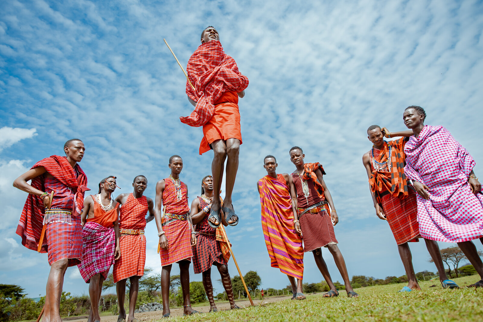 Maasai warriors in red robes performing a traditional leaping welcome dance