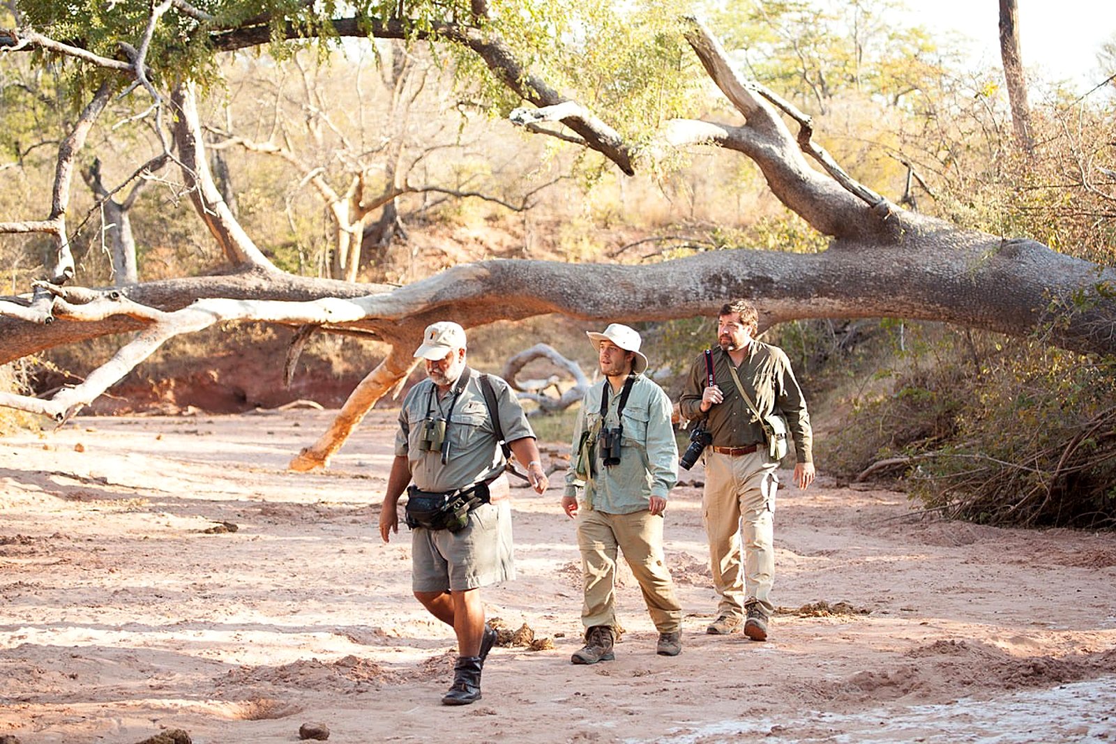 Walkers crossing a dry riverbed with an armed guide