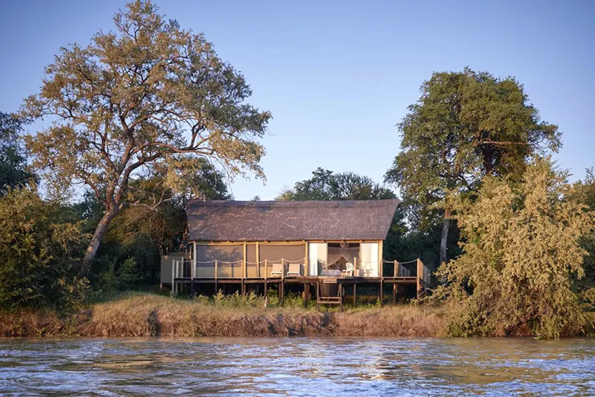 Riverfront tented suite exterior seen from the Zambezi at golden hour
