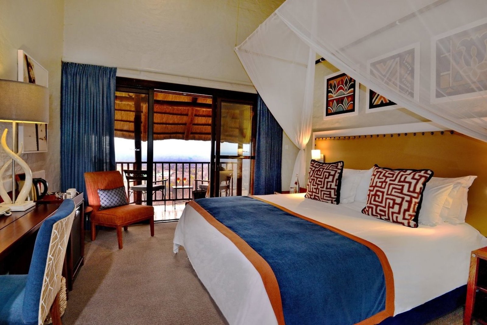An open-plan living space with sliding doors to the patio at Victoria Falls Safari Suites