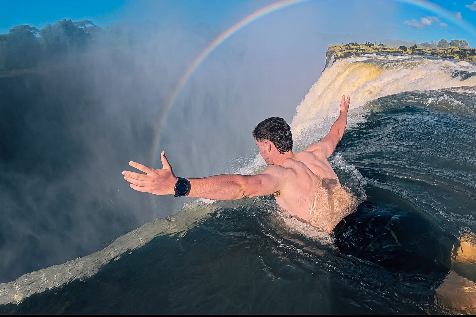 Swimmers at the edge of Devils Pool on the lip of Victoria Falls