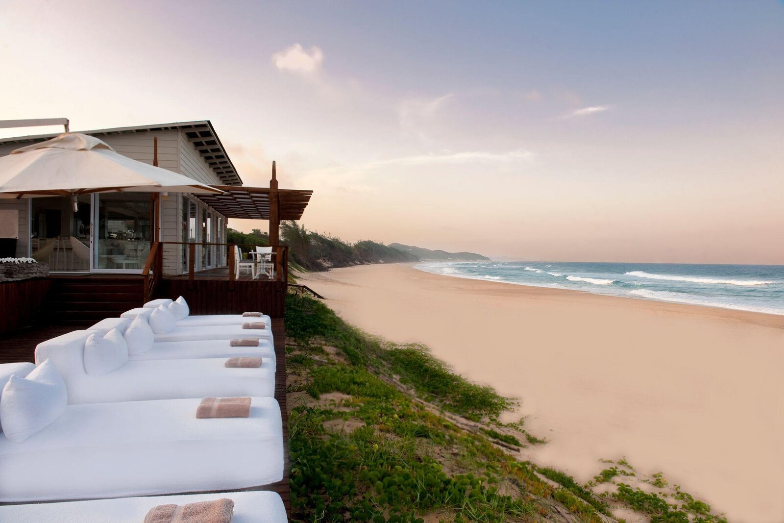 Loungers on an empty beach beneath the dunes at White Pearl Ponta Mamoli, southern Mozambique