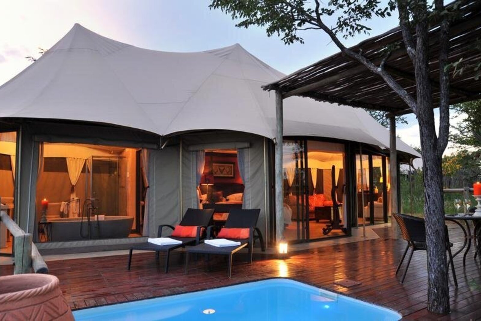 A tented suite with a private plunge pool lit at dusk in Zimbabwe