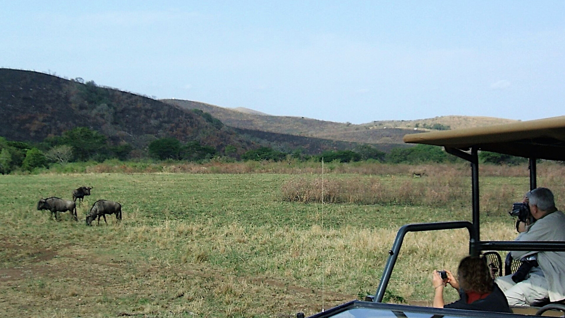 A game-viewing vehicle on an open plains drive at sunrise in the Kruger