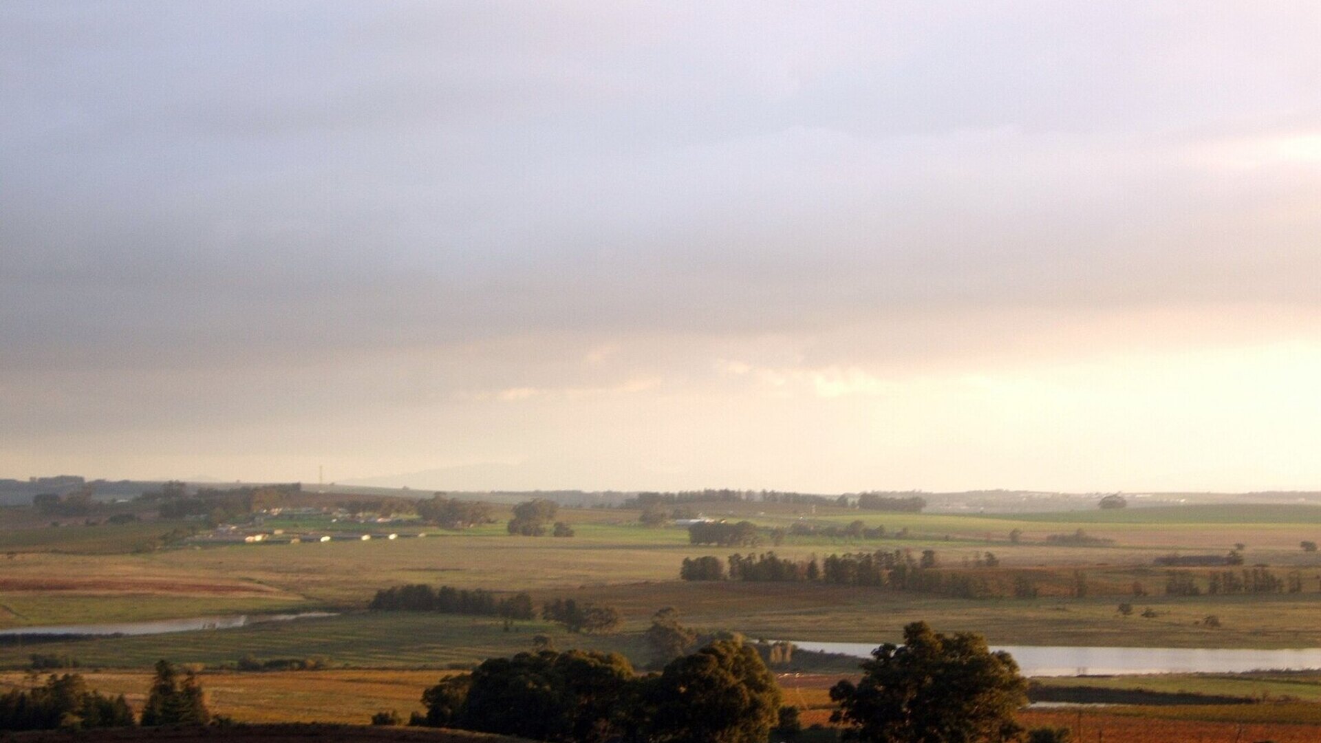 A couple watching a golden sunset over the Cape Winelands vineyards at the start of their all-inclusive honeymoon