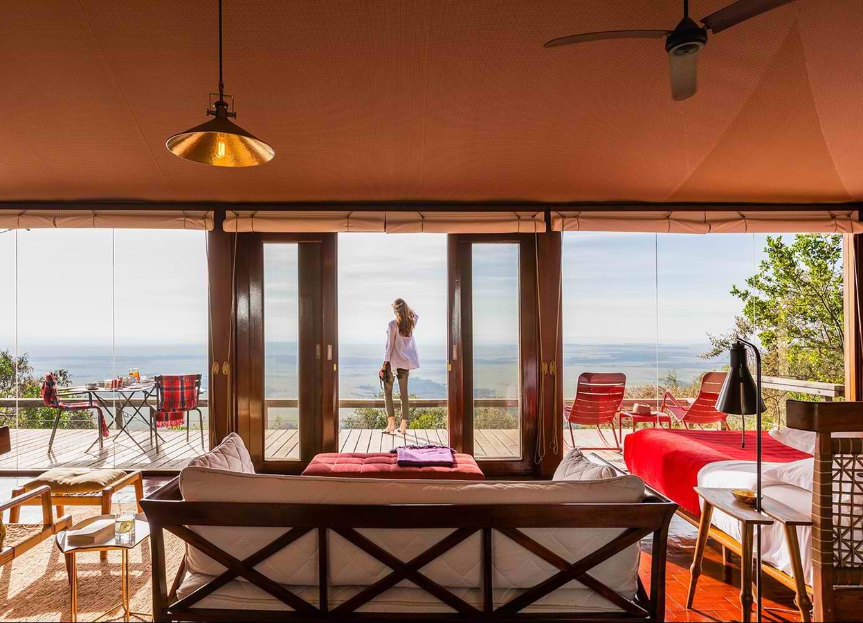Angama Mara luxury tented suite with floor-to-ceiling glass overlooking the Masai Mara plains at sunrise
