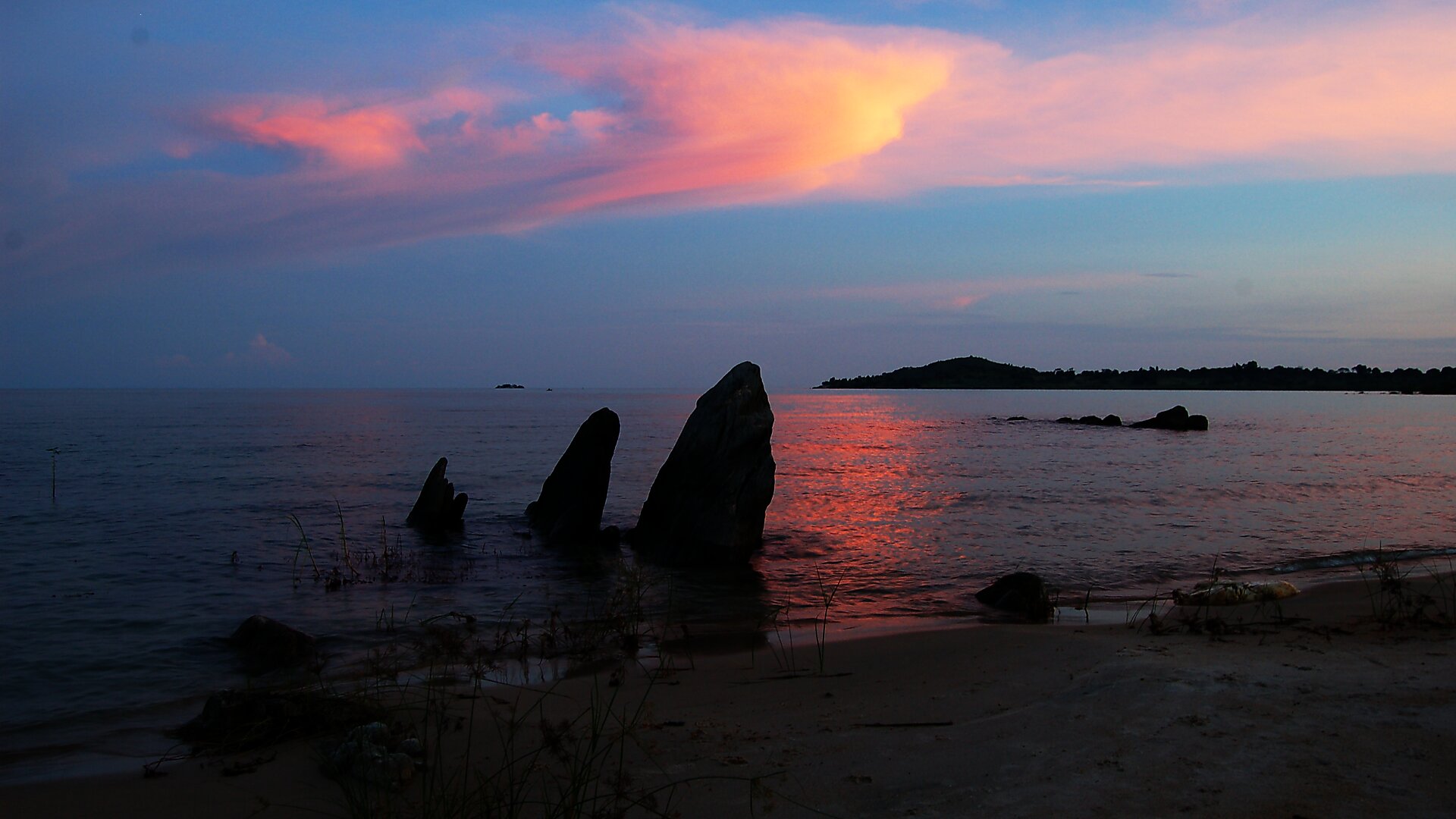 Sunset over Lake Malawi with rocky shore and pink clouds