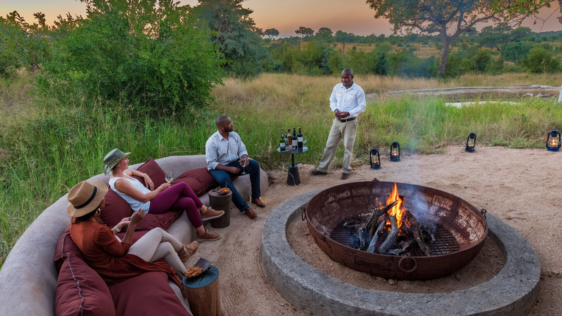 A fire-lit open-air deck under a star-filled African sky at a luxury safari lodge