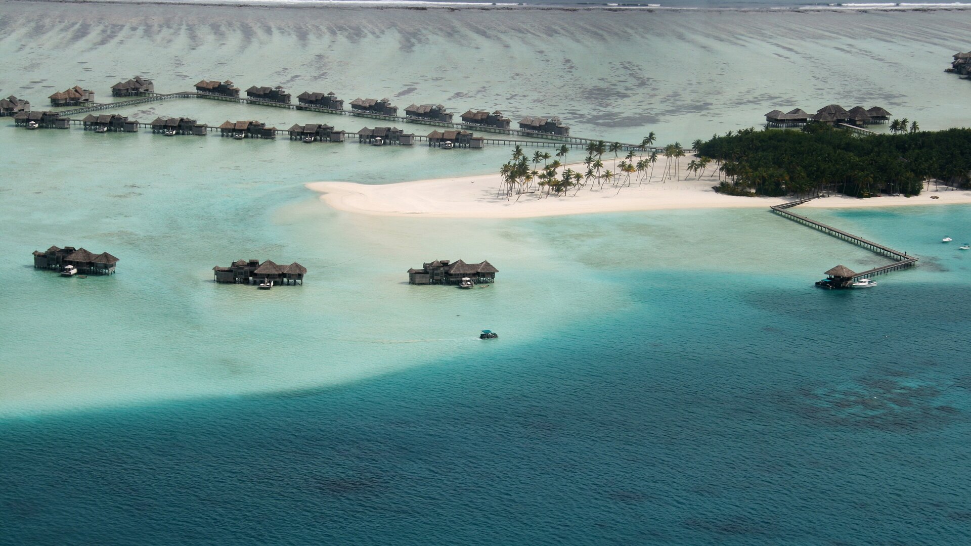 Aerial view of a Maldives island ringed by turquoise lagoon and overwater villas — the dry season, December to April, is the best time to visit the Maldives