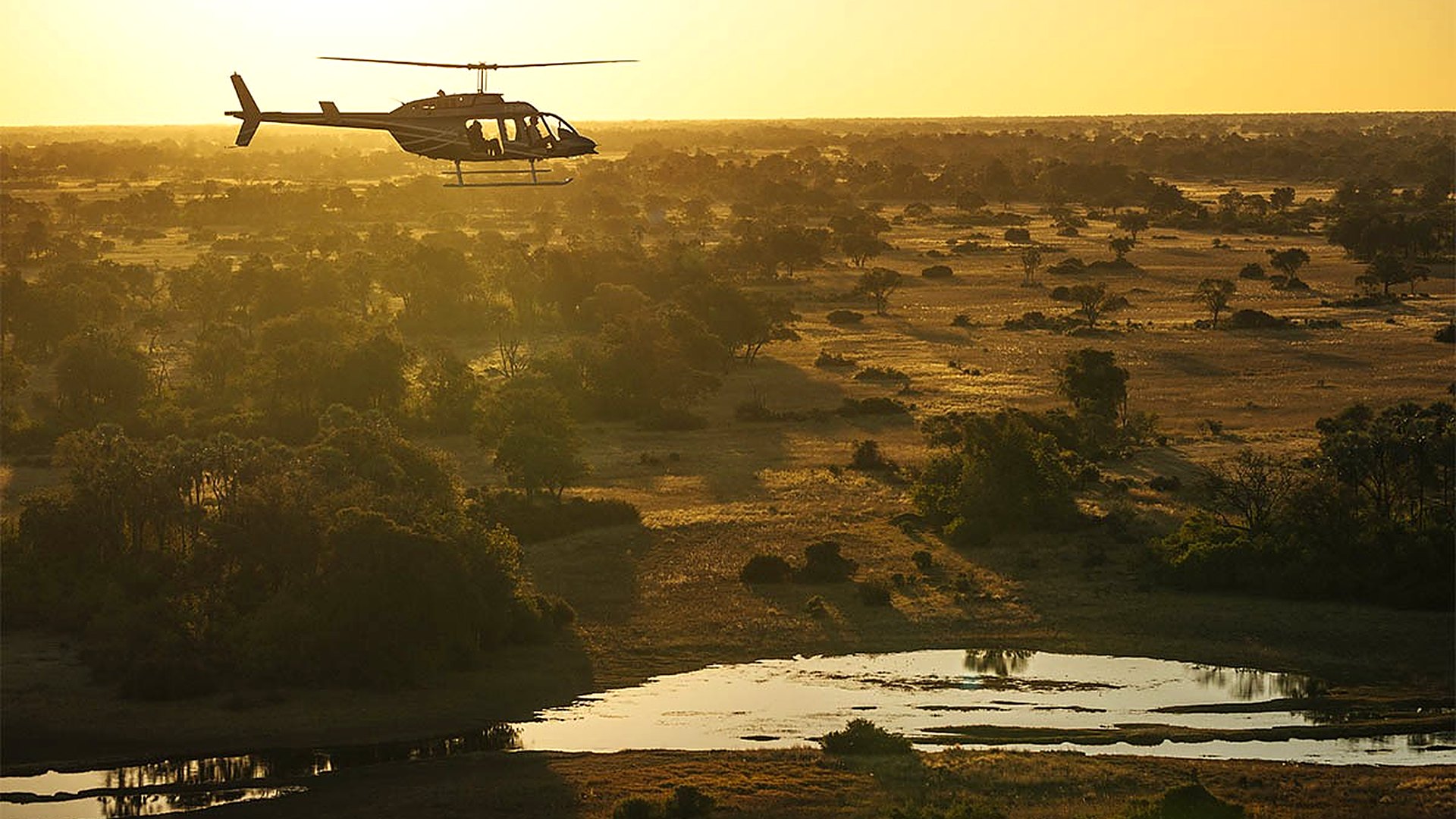 A helicopter flight over the vast Okavango Delta at golden hour in Botswana
