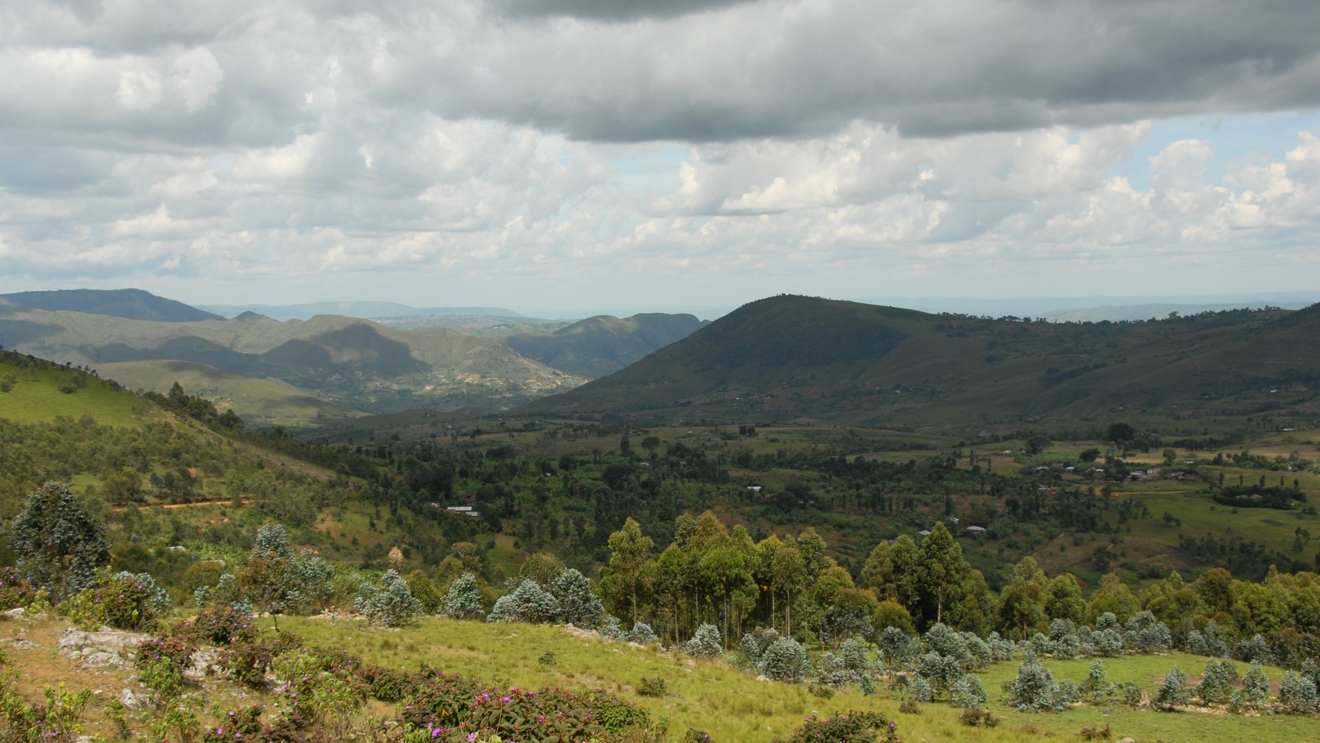 Burundi's green highland hills rolling toward distant mountains under a wide cloudy sky