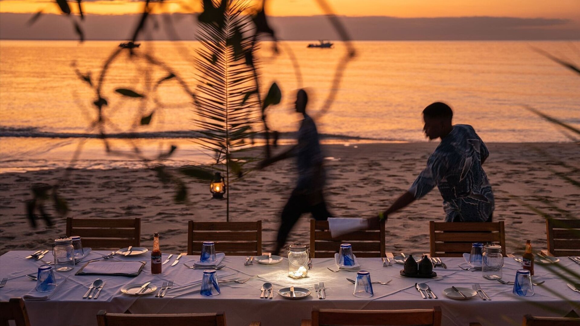 Romantic beach dinner at sunset on an Indian Ocean island after an African safari honeymoon