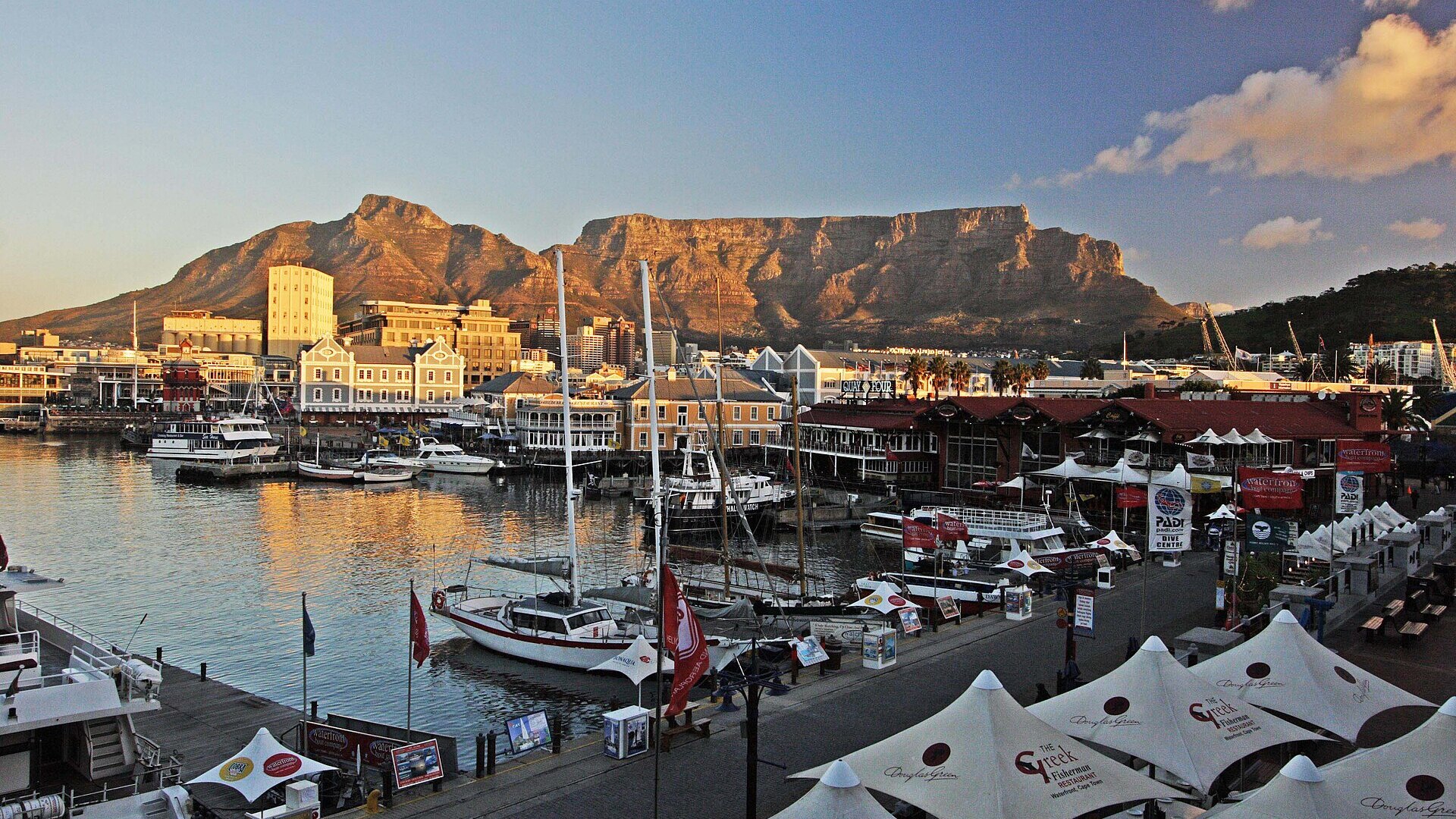 A yacht sailing on Table Bay at sunset with Table Mountain glowing behind Cape Town