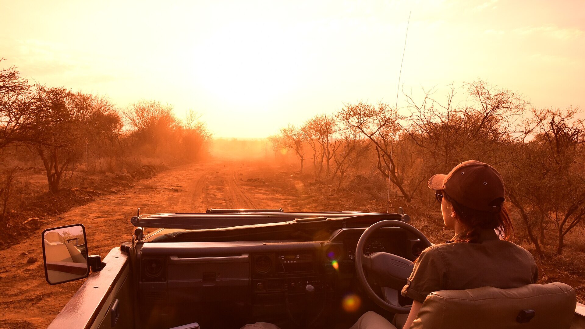 Open safari vehicle facing a golden festive-season African sunset — a Christmas safari in Africa
