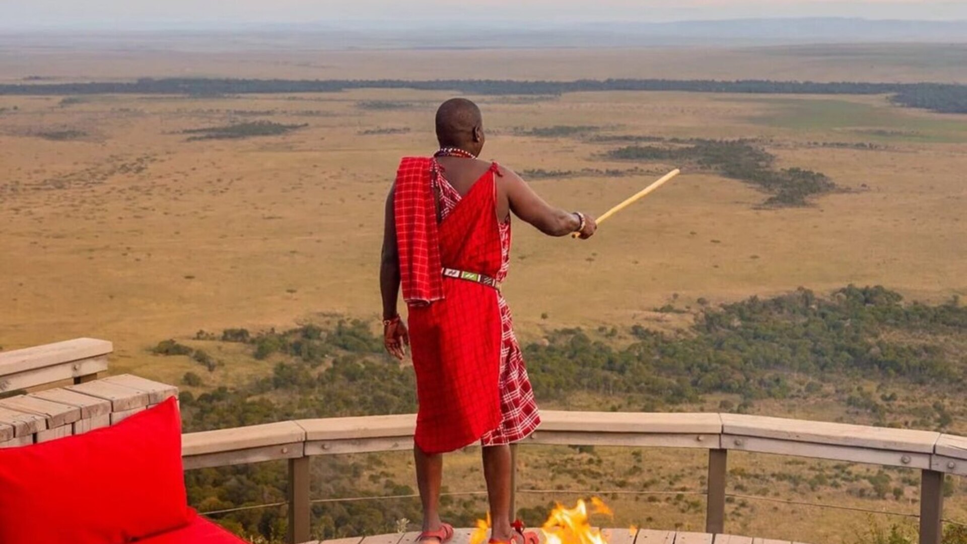 A Maasai warrior at a sundowner overlooking the plains at golden hour — a couples safari in Africa with Beyond Africa Safaris