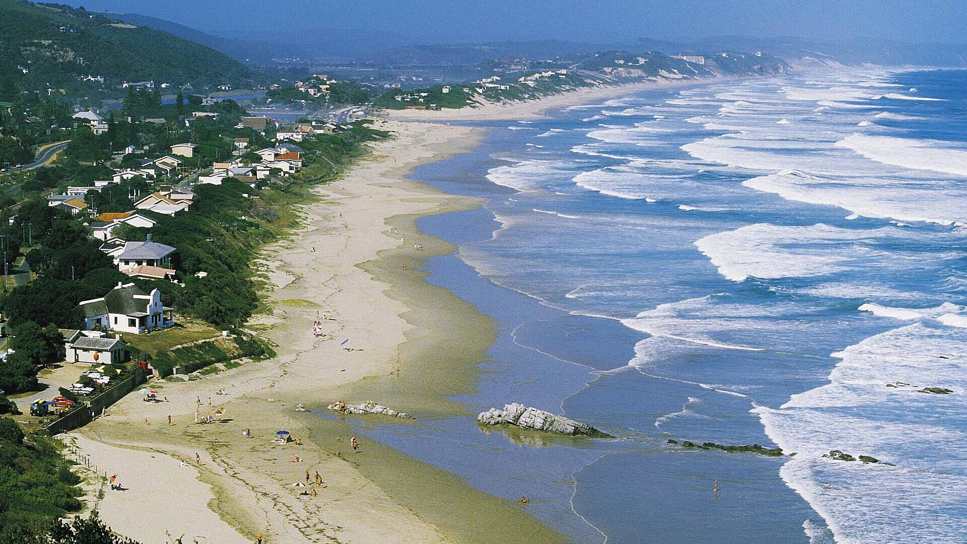A family on a golden beach with a lagoon and forest behind on a Garden Route family holiday, South Africa