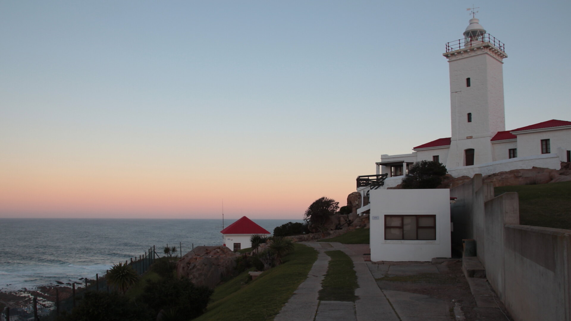 A couple watching a golden-hour sunset over the sea from a romantic lodge deck on the Garden Route, South Africa