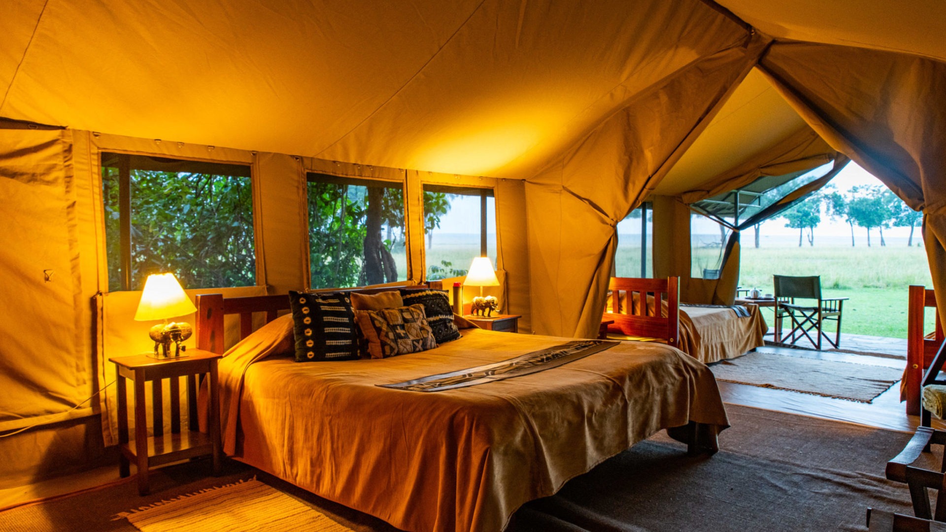 Governors' Camp classic tented camp on the banks of the Mara River at sunrise with elephants and hippos grazing