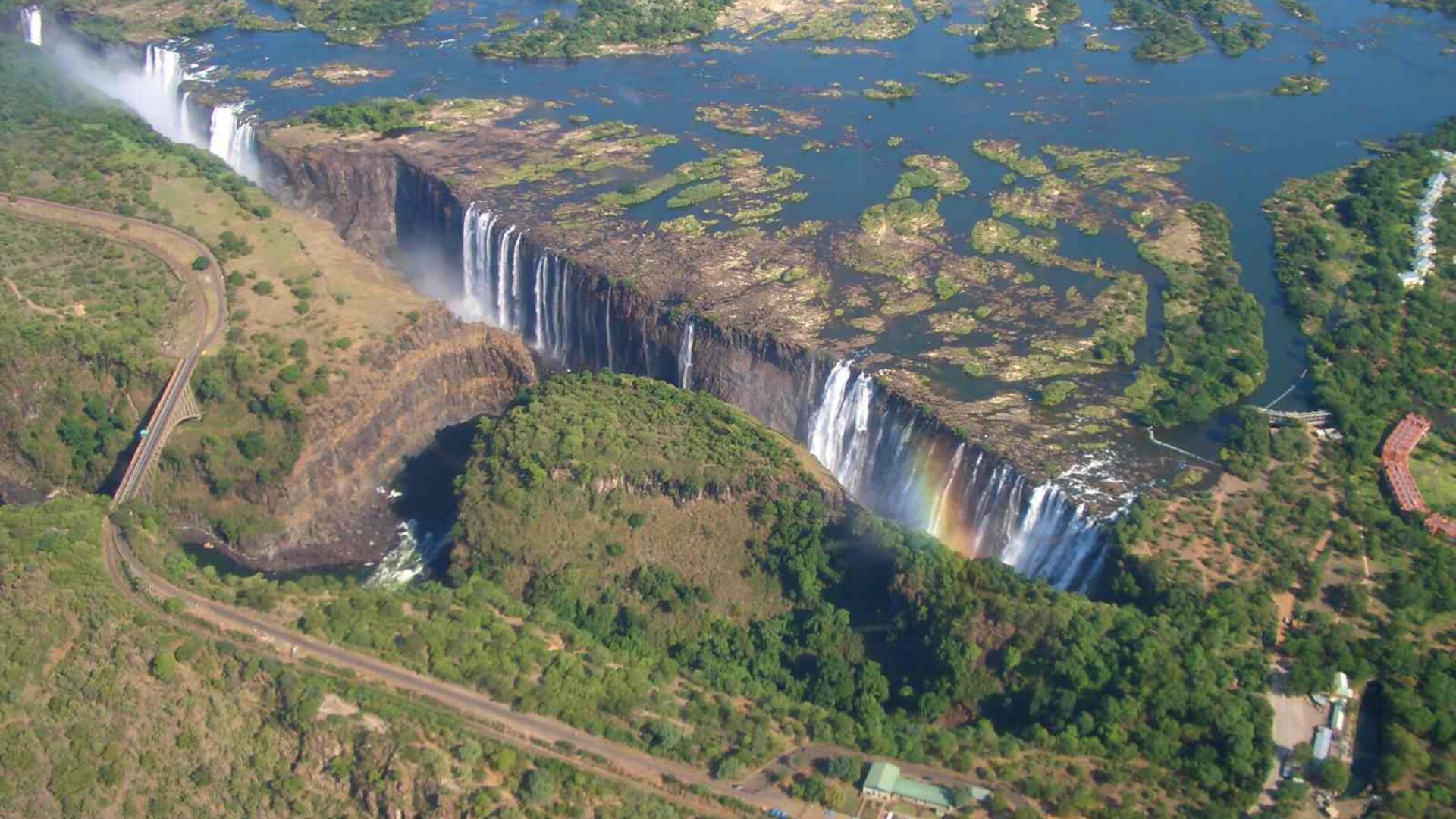 A luxury safari helicopter flying low over an African river and floodplain at golden hour