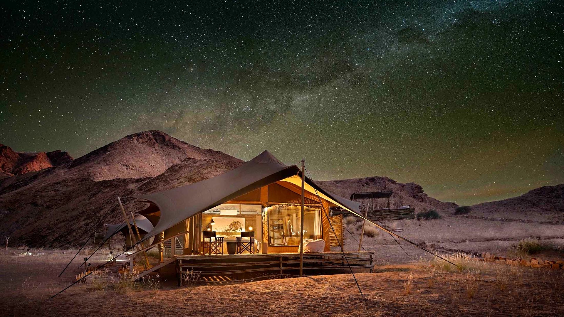 Canvas suites of Hoanib Valley Camp glowing at dusk on the floor of the remote Hoanib Valley
