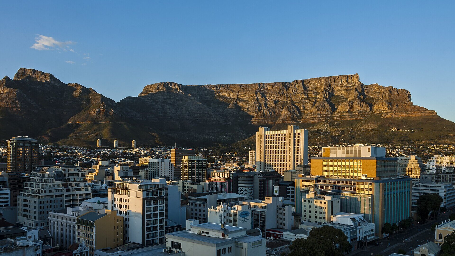 Table Mountain and the V&A Waterfront glowing at dusk above a calm, safe Cape Town harbour