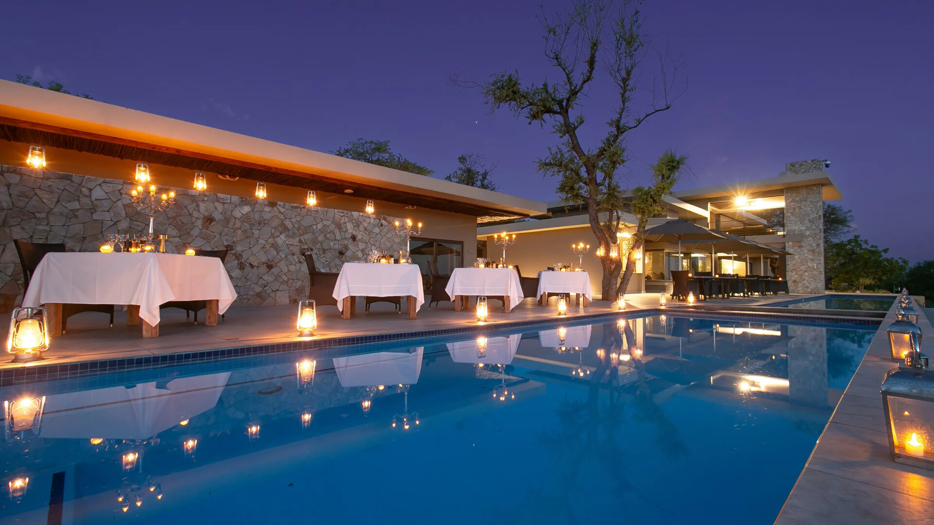 The candlelit pool and villa deck at Jamala Madikwe Royal Safari Lodge at dusk in the Madikwe Game Reserve