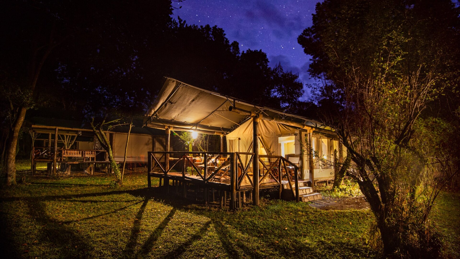 Karen Blixen Camp luxury tent and riverside deck on the Mara River in the Mara North Conservancy at golden hour